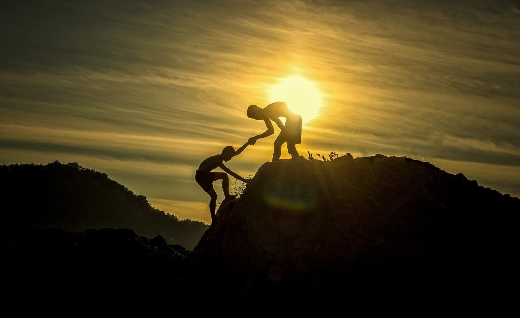 boy helping hand to boy on mountain