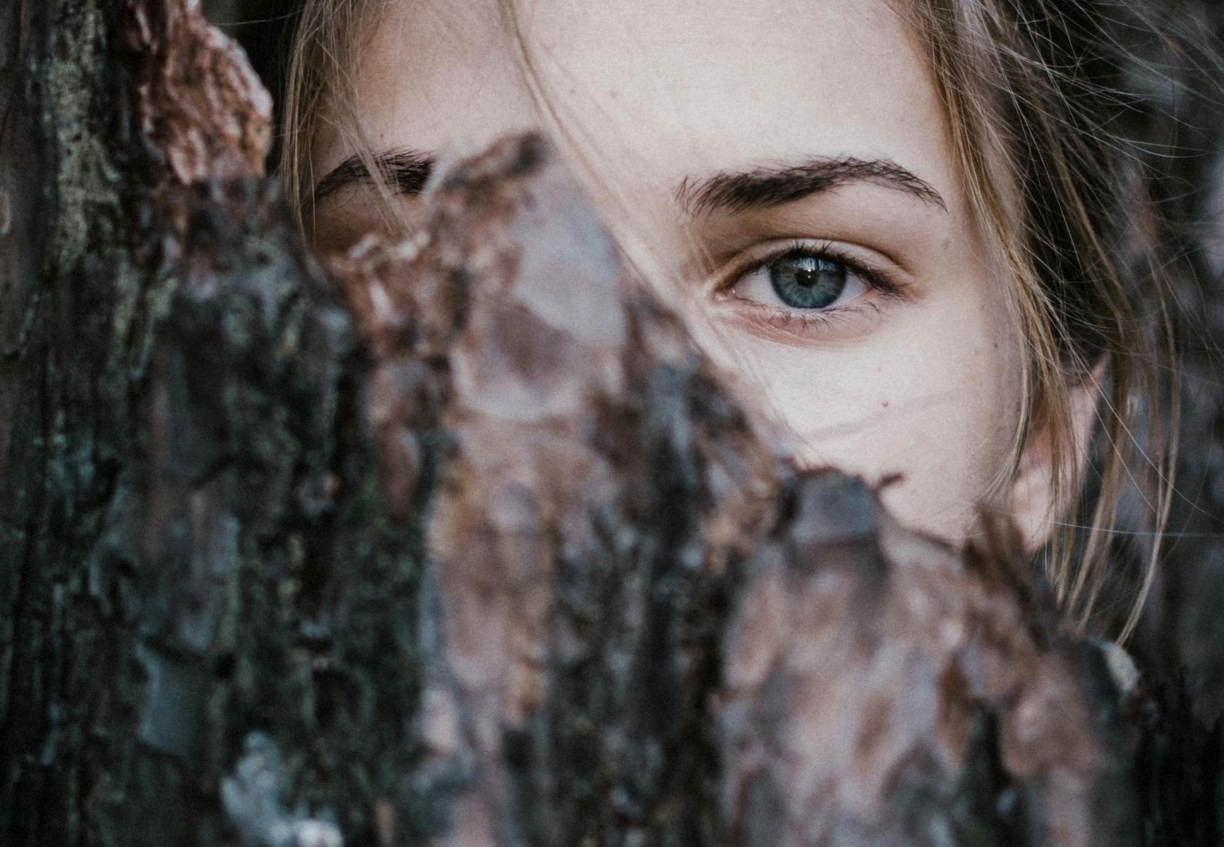 calm woman behind tree bark in park