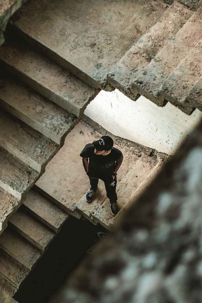 man wearing black crew neck t shirt standing on concrete stairs